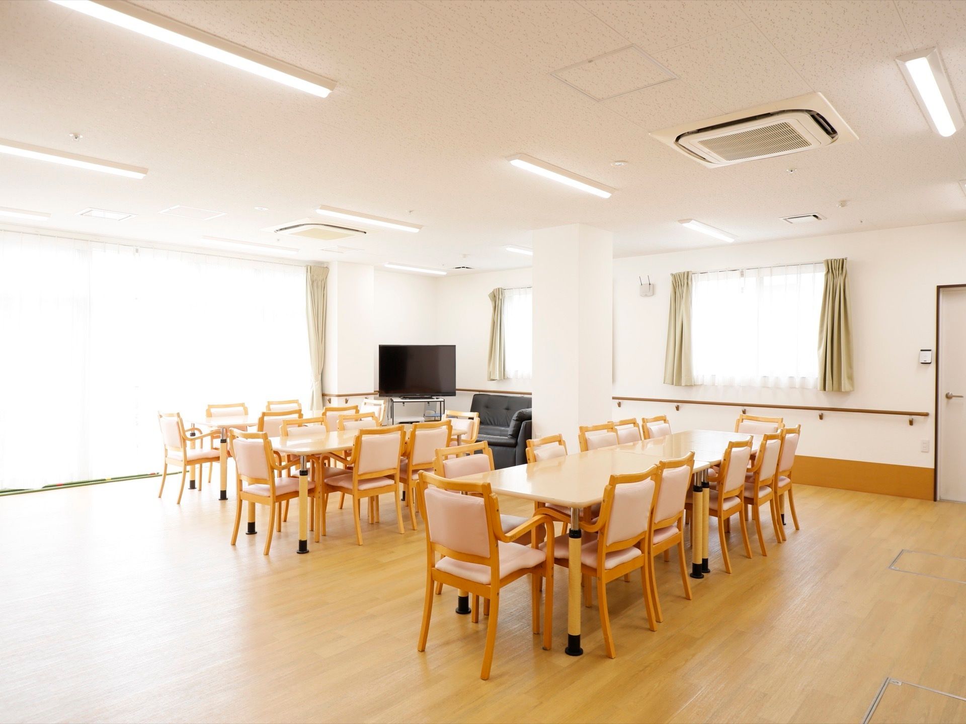 広い室内の中央にイスとテーブルが複数設置されている。部屋の窓は大きく、外から太陽光が入って室内は明るい。