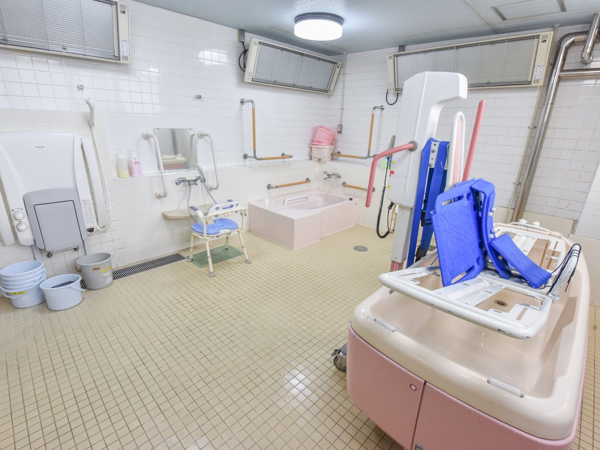 手すりが備え付けられた浴槽に、横になったまま入浴が可能な介護浴槽、シャワーなどが備え付けられた広い浴室。