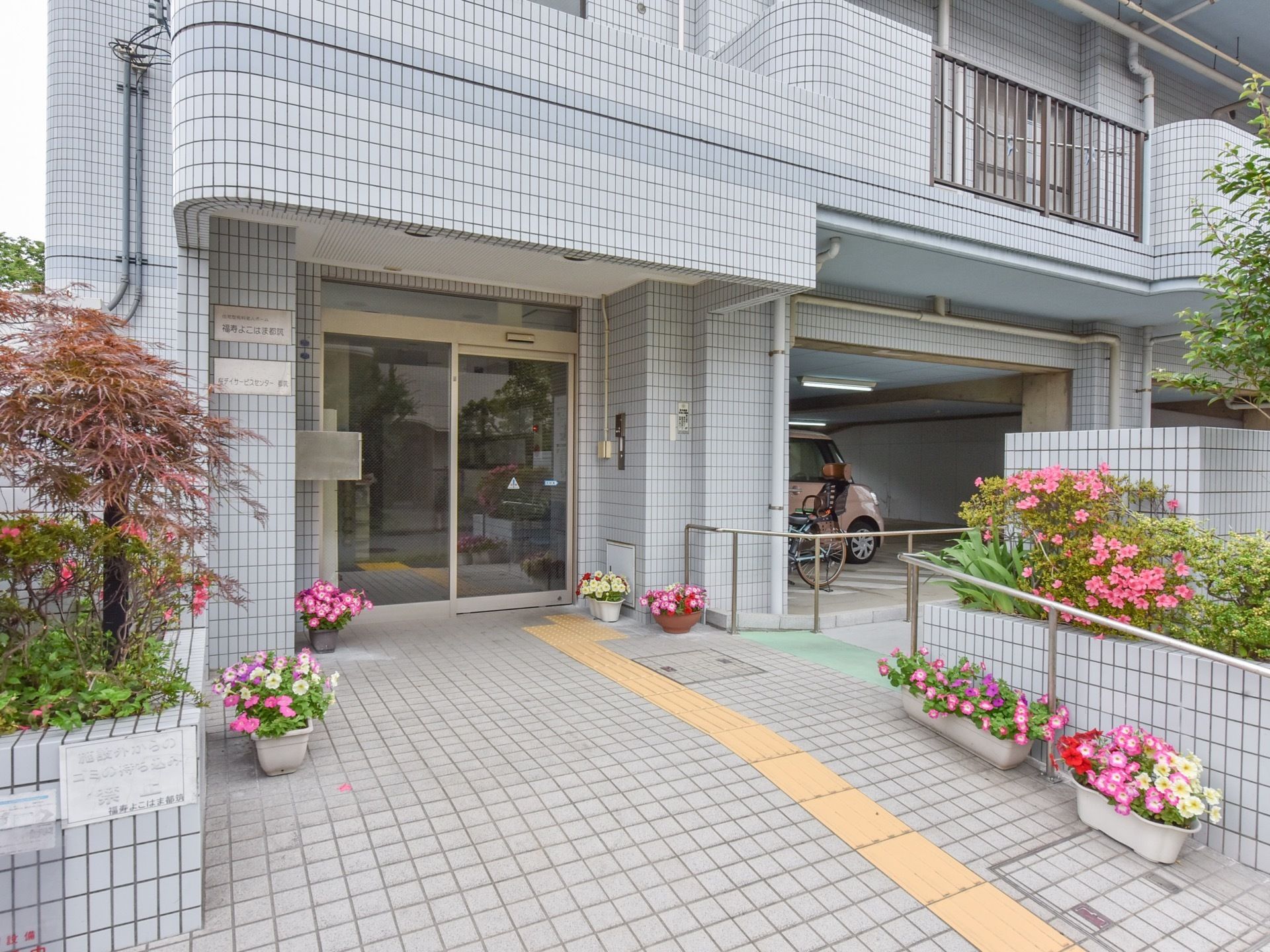グレーのタイル張りの壁が特徴的な外観をしている。建物の一階部分は駐車場になっており、スロープがついている。