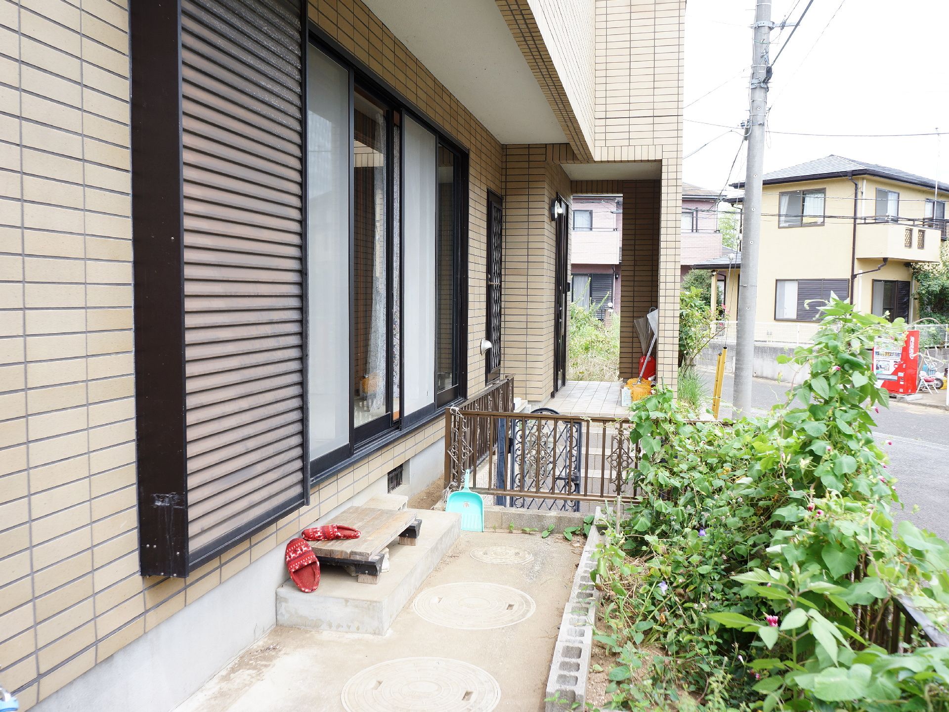 施設の掃き出し窓の外には外に出られるように履物が用意されている。右側には様々な植物が植えられ、ブロックで仕切りが作られている。