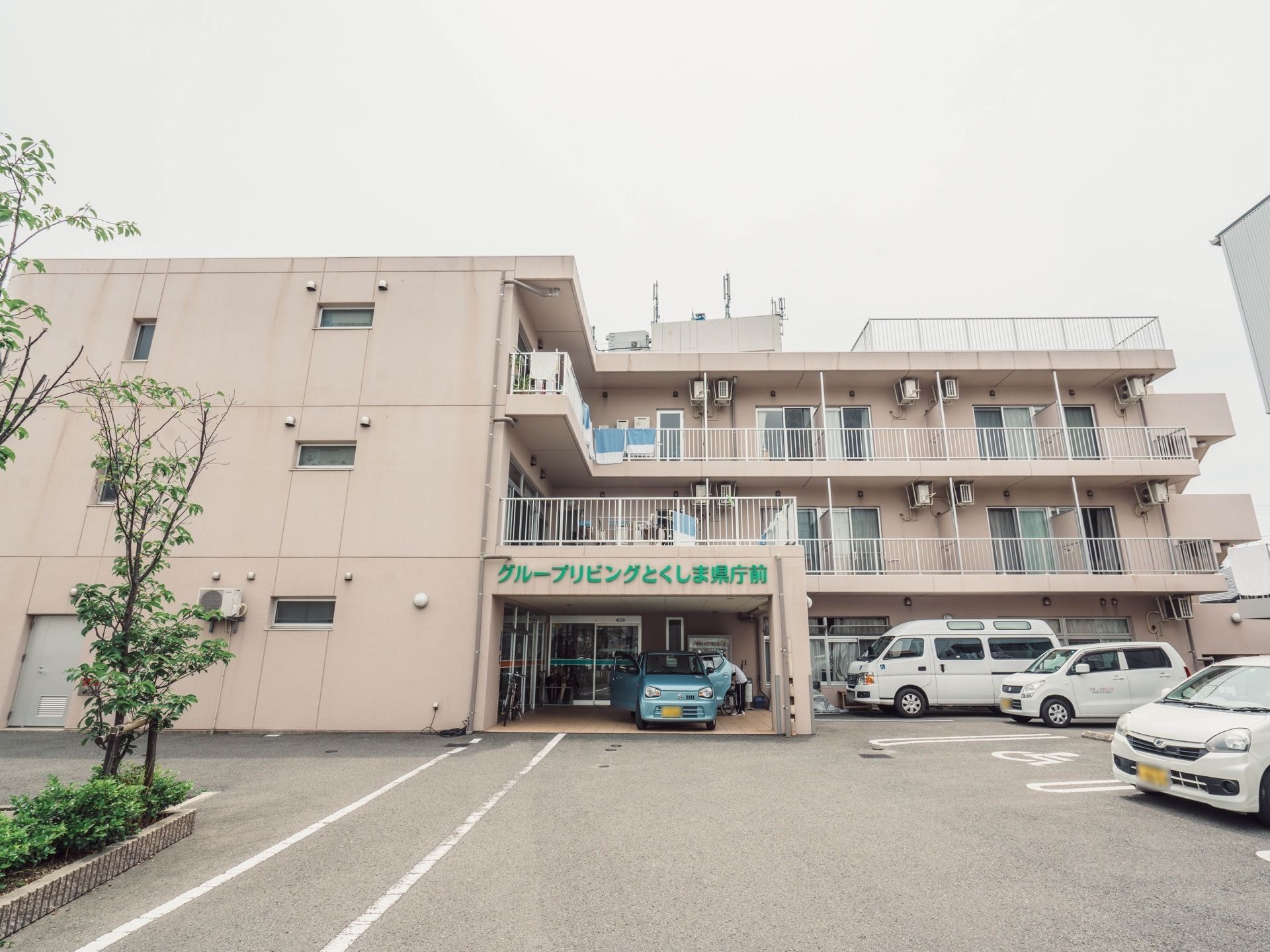 正面から見た施設建物。２階から上の居室の窓からはベランダに出られる。玄関口のひさしはバルコニーにもなっている。