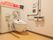 共用トイレの便座は、床ではなく壁から生えたような特徴的なつくりをしている。右手側に折りたたみ可能な手すりがある。