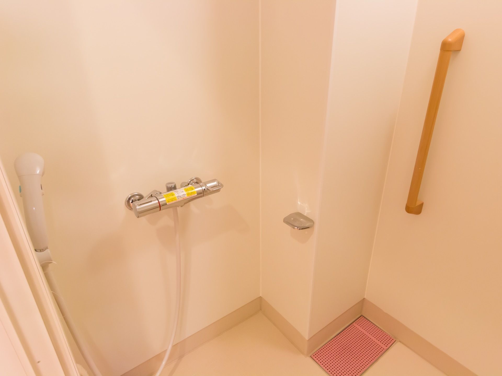 シャワールームがある。壁に縦方向の大きな手すりが設置され、水栓の近くには石鹸置きが取り付けられている。