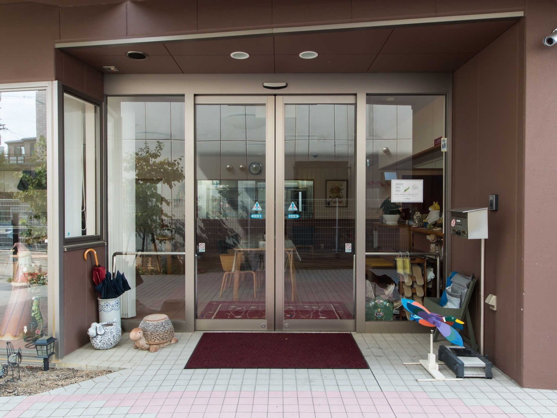玄関はガラスの自動扉である。陶器の傘立てに傘が２本入っている。玄関の右側に、インターホンと郵便受けが設置されている。