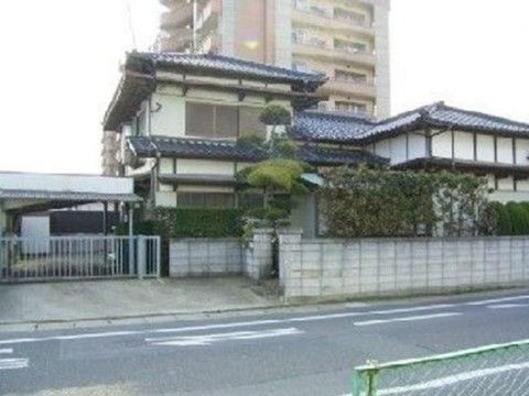 美しく剪定された庭木のある、瓦ぶき屋根の戸建て住宅