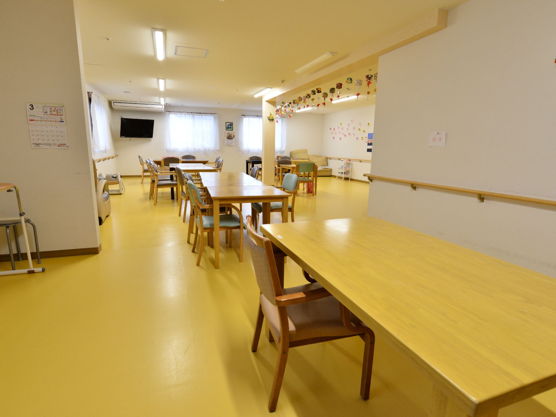 いくつかのテーブルを設置した食堂。車いすのままテーブルにつける。壁には手すりが設置されており、段差はない。