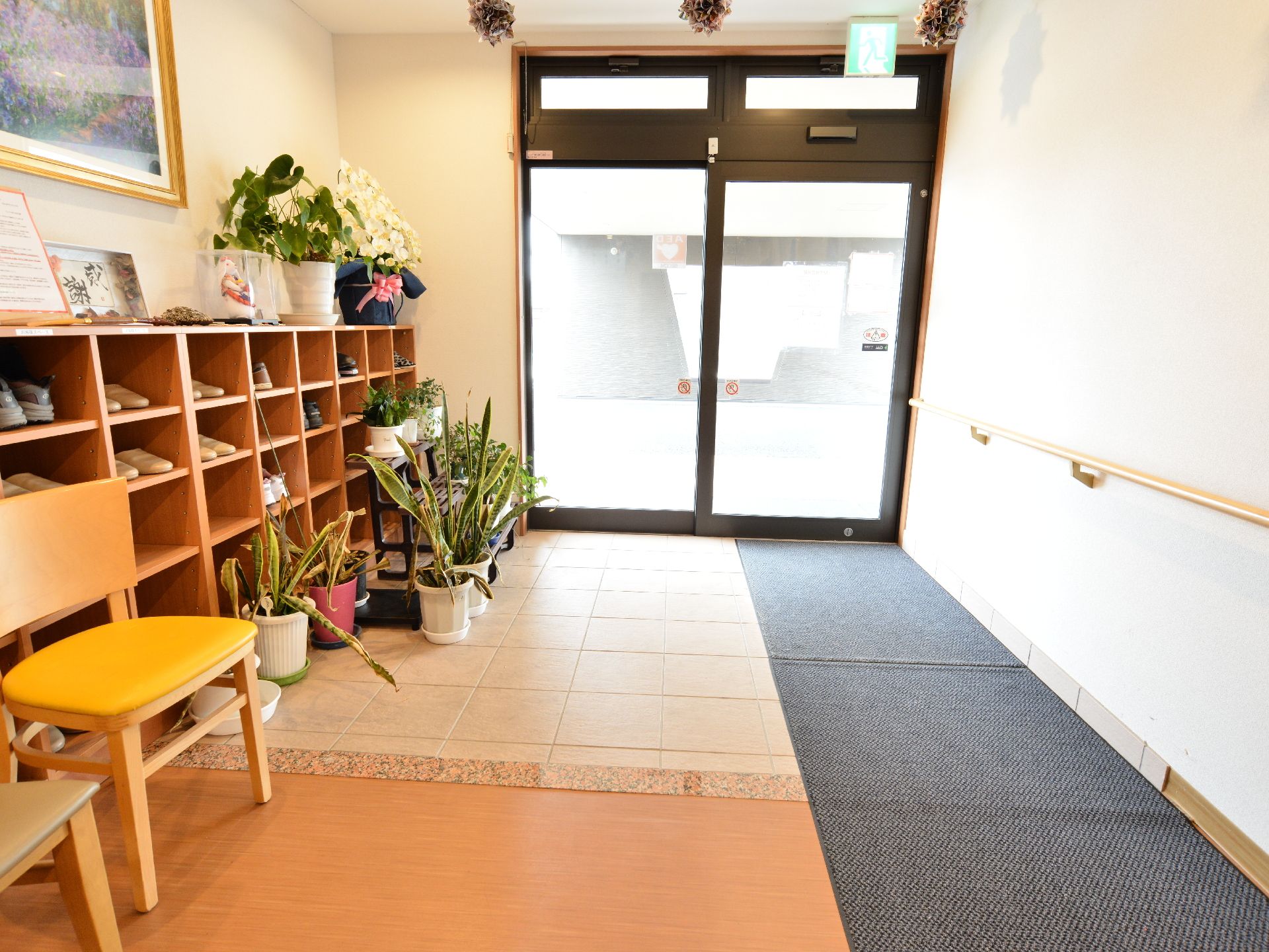 施設の入り口は自動ドア。片方に手すりを設置している。滑らないようにカーペット敷きになっている。靴箱も完備。