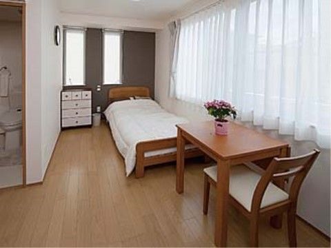 ベッドや収納家具、テーブルや椅子が置かれている個室