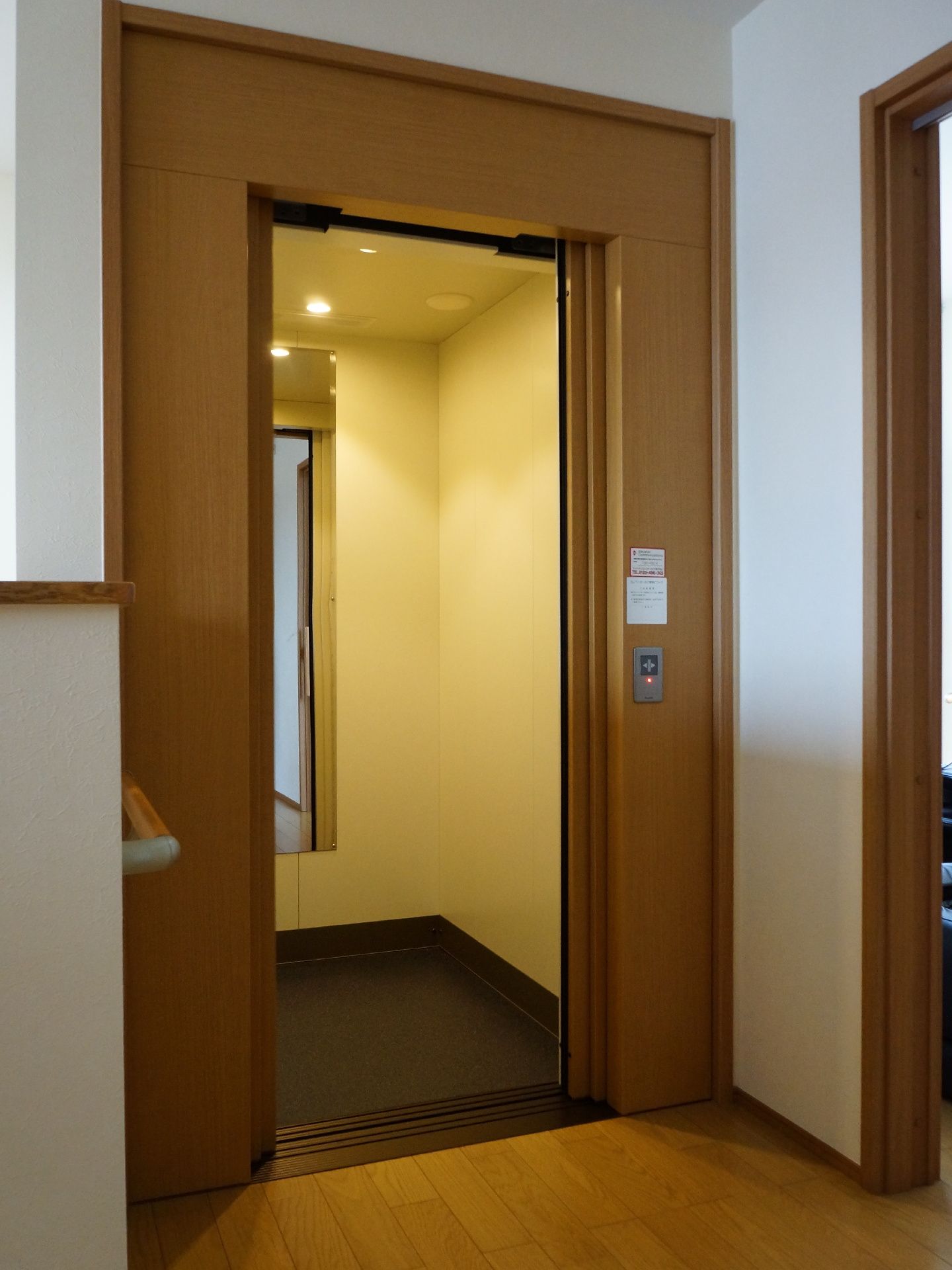 優しい印象のエレベーターとなっている。入居者様が利用しやすい工夫がされている。壁には手すりがあり、安全となっている。