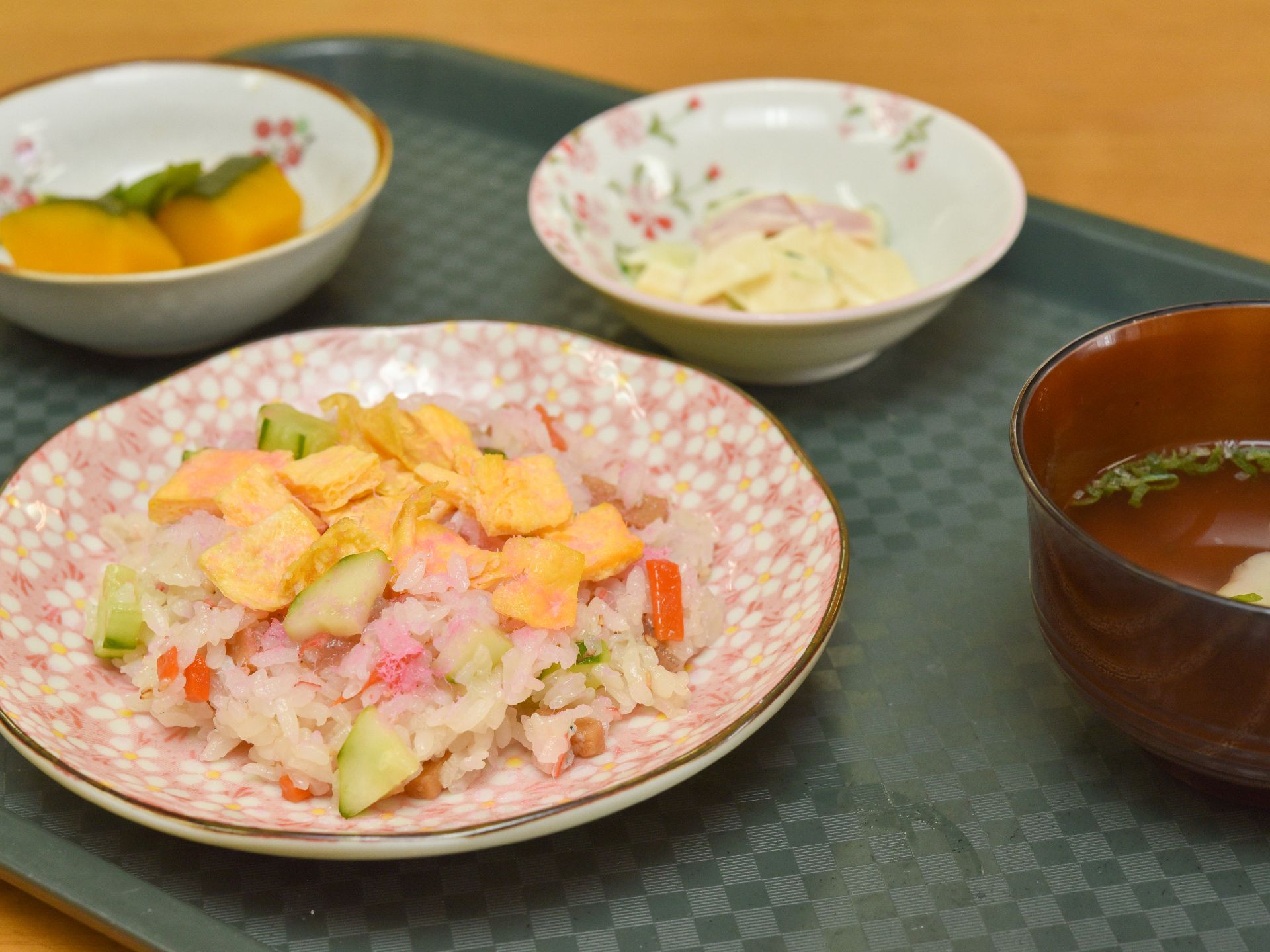 カボチャの煮物やサラダ、豆腐のお味噌汁、彩豊かなちらし寿司が並んでいるトレー