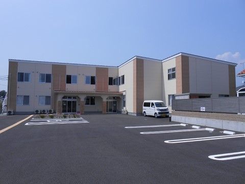 施設建物の前面に広々とした駐車場を完備した２階建ての施設の外観