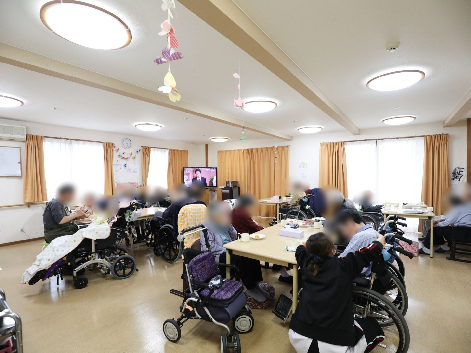 複数の窓がある明るくて広い共用スペース。食事をしたり、各種催しなどに利用可能である。車椅子のまま利用できる。