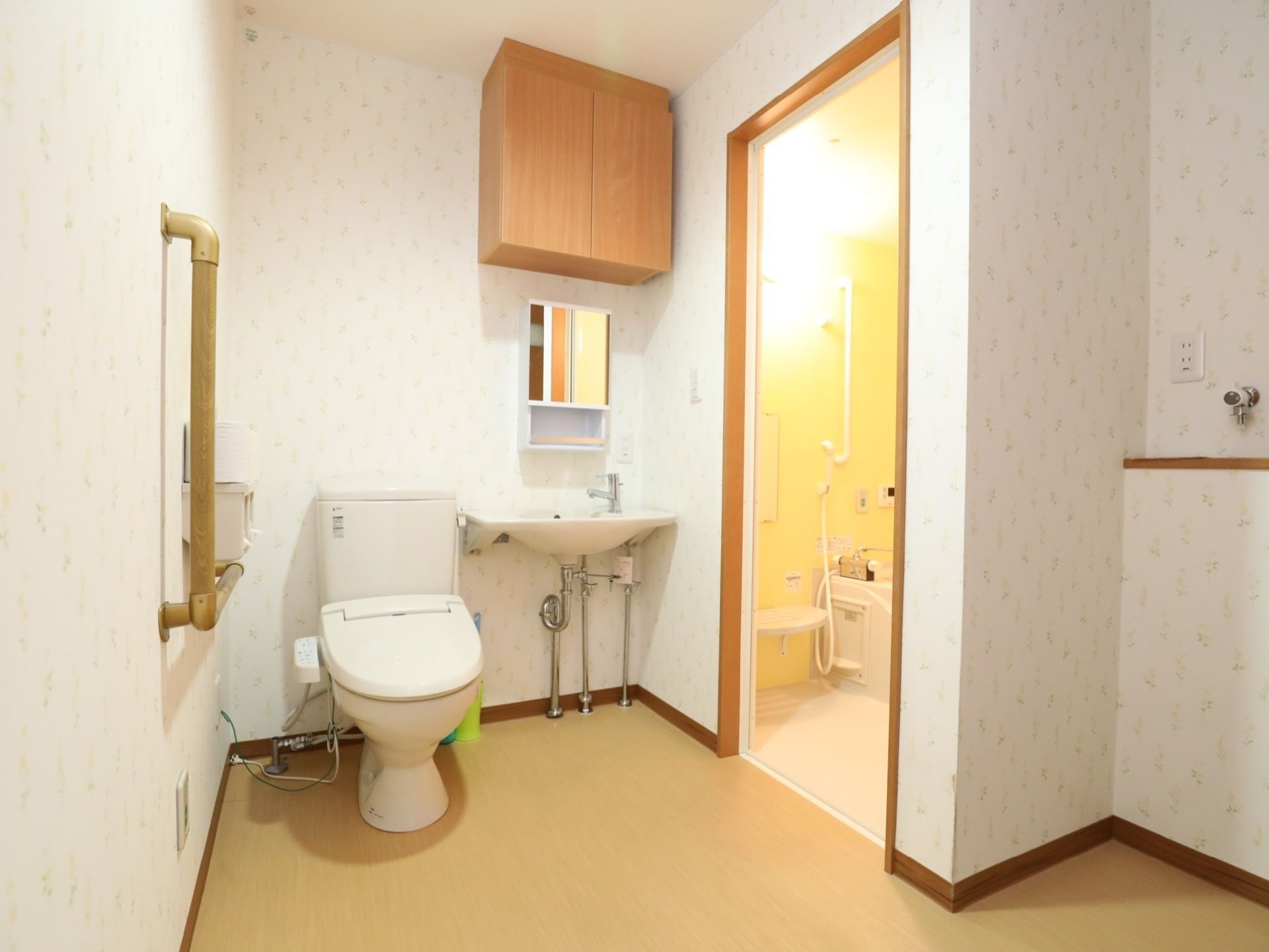 居室のトイレと洗面台である。トイレの奥は浴室で、入り口はバリアフリーになっている。手前に洗濯機設置スペースがある。