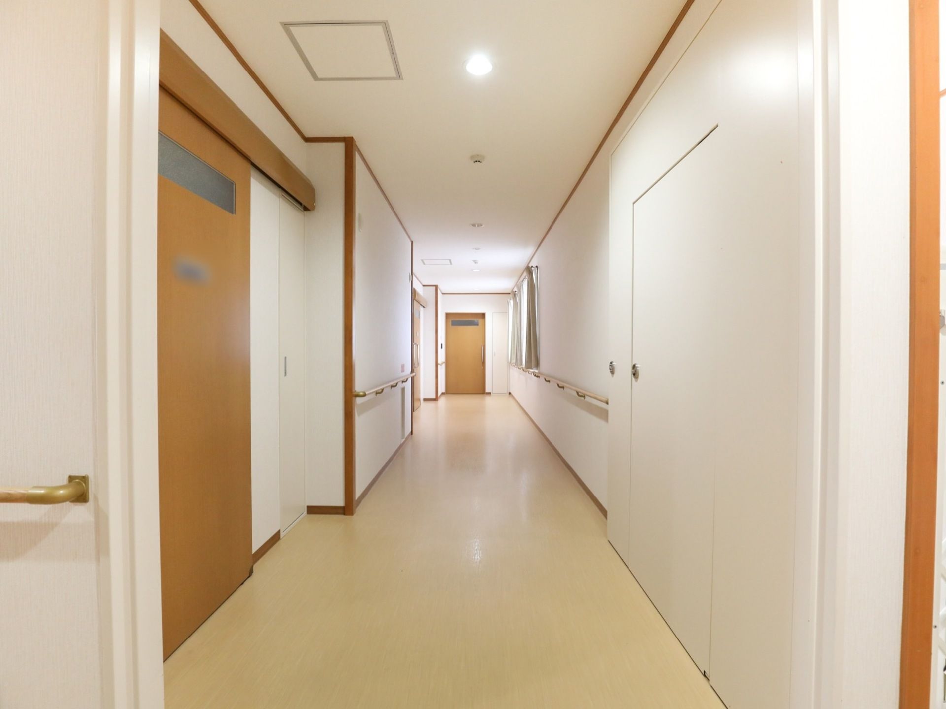 通路がまっすぐ伸びている。両サイドの壁には手すりがある。窓からの光とダウンライトで明るさも十分確保している。
