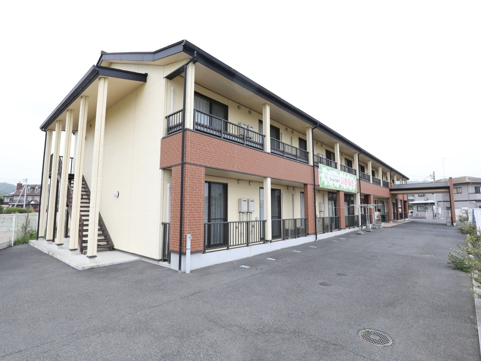 木造2階建ての施設の外観である。周囲に日光を遮るものが無く、たいへん日当たりが良い。2階へ続く外階段がある。
