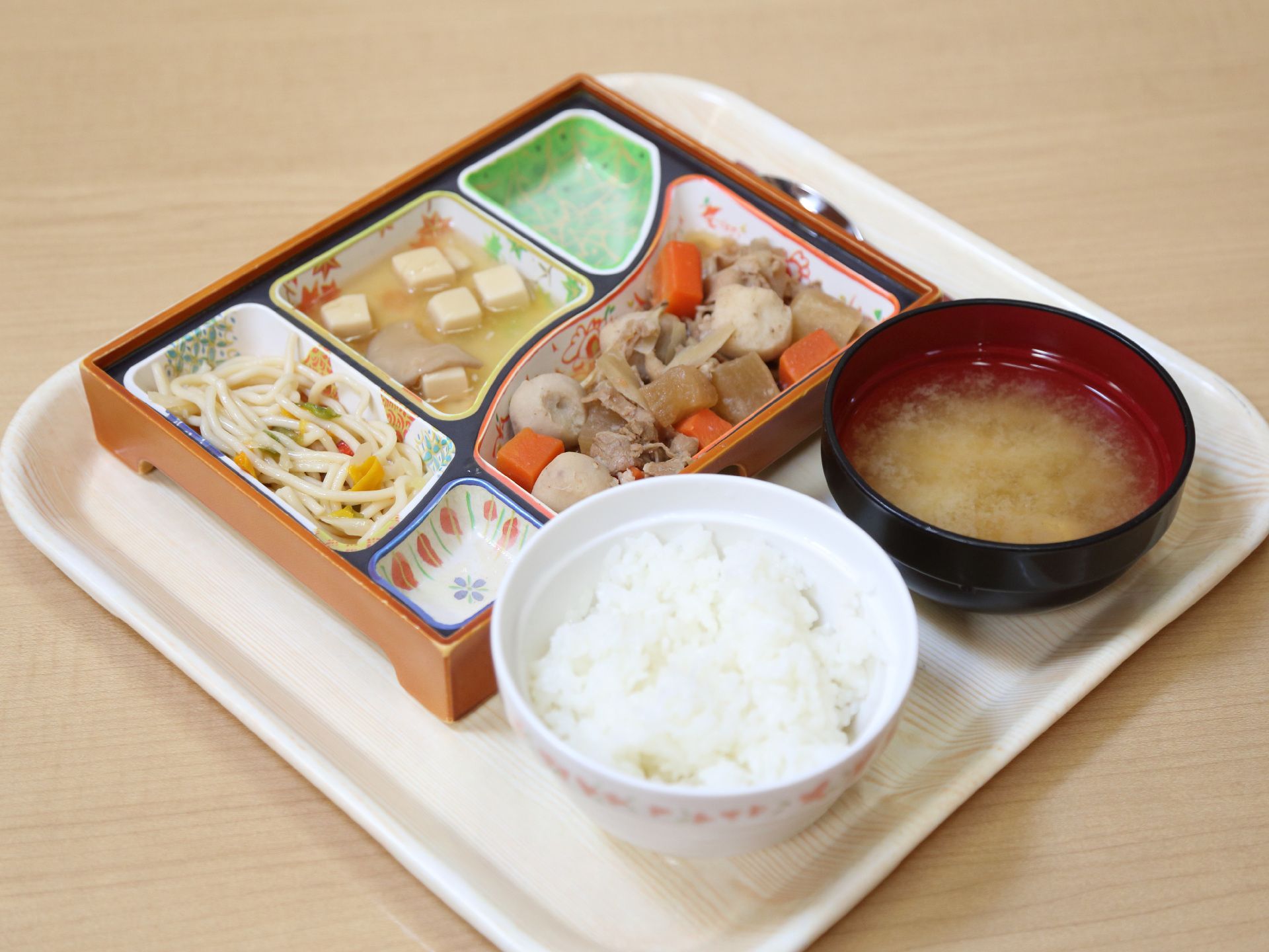 ご飯とお味噌汁、煮物やサラダなどが置かれているトレー