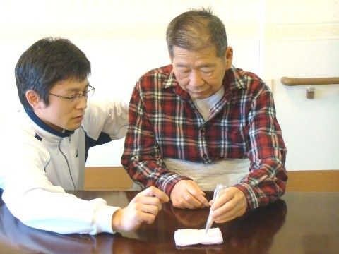 専門スタッフのサポートを受けながら、手先のリハビリを行う男性入居者