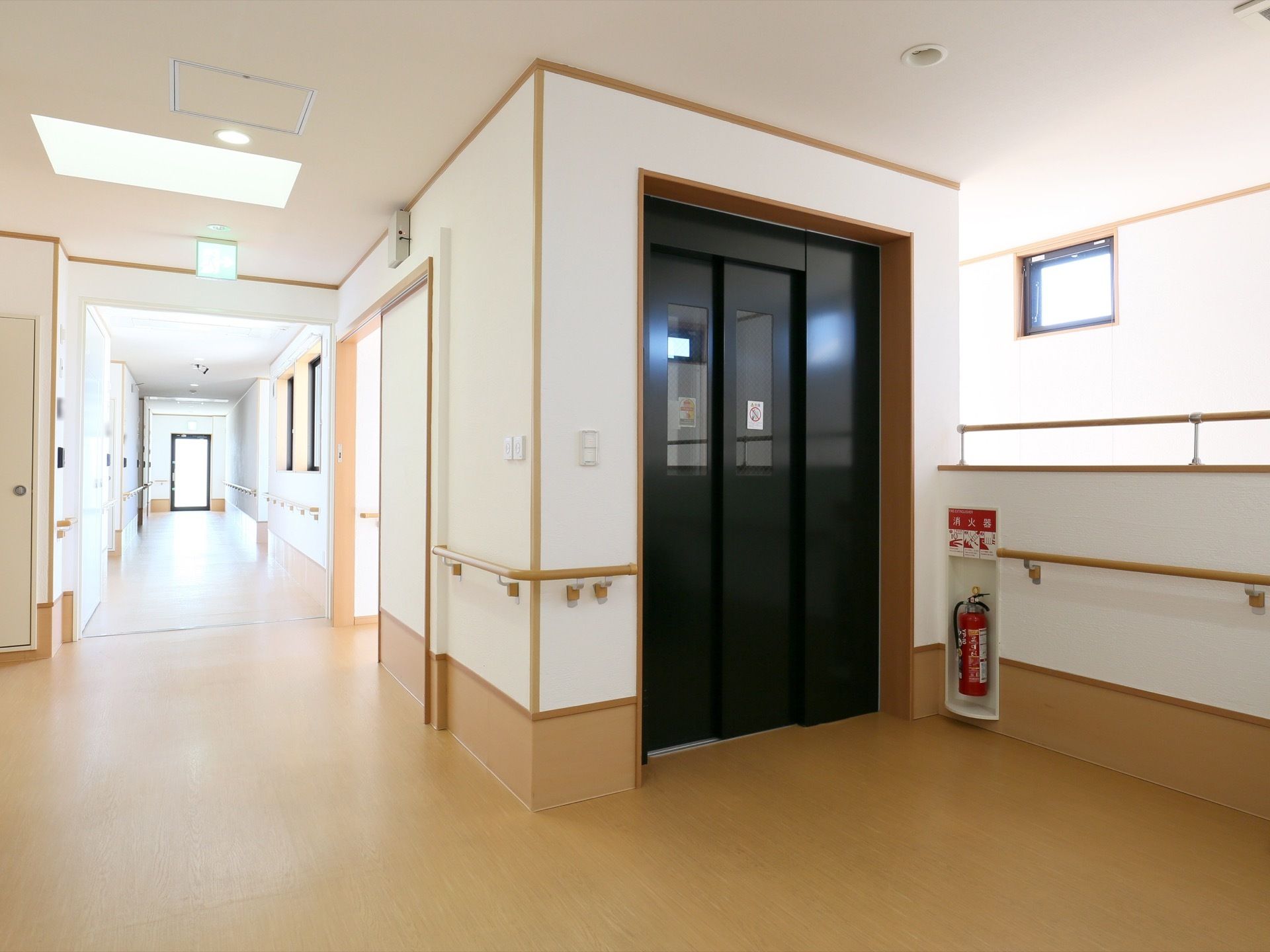 黒い扉のエレベーターがあり、扉には窓ガラスが開いている。その奥のスペースは階下からの吹き抜けになっている。