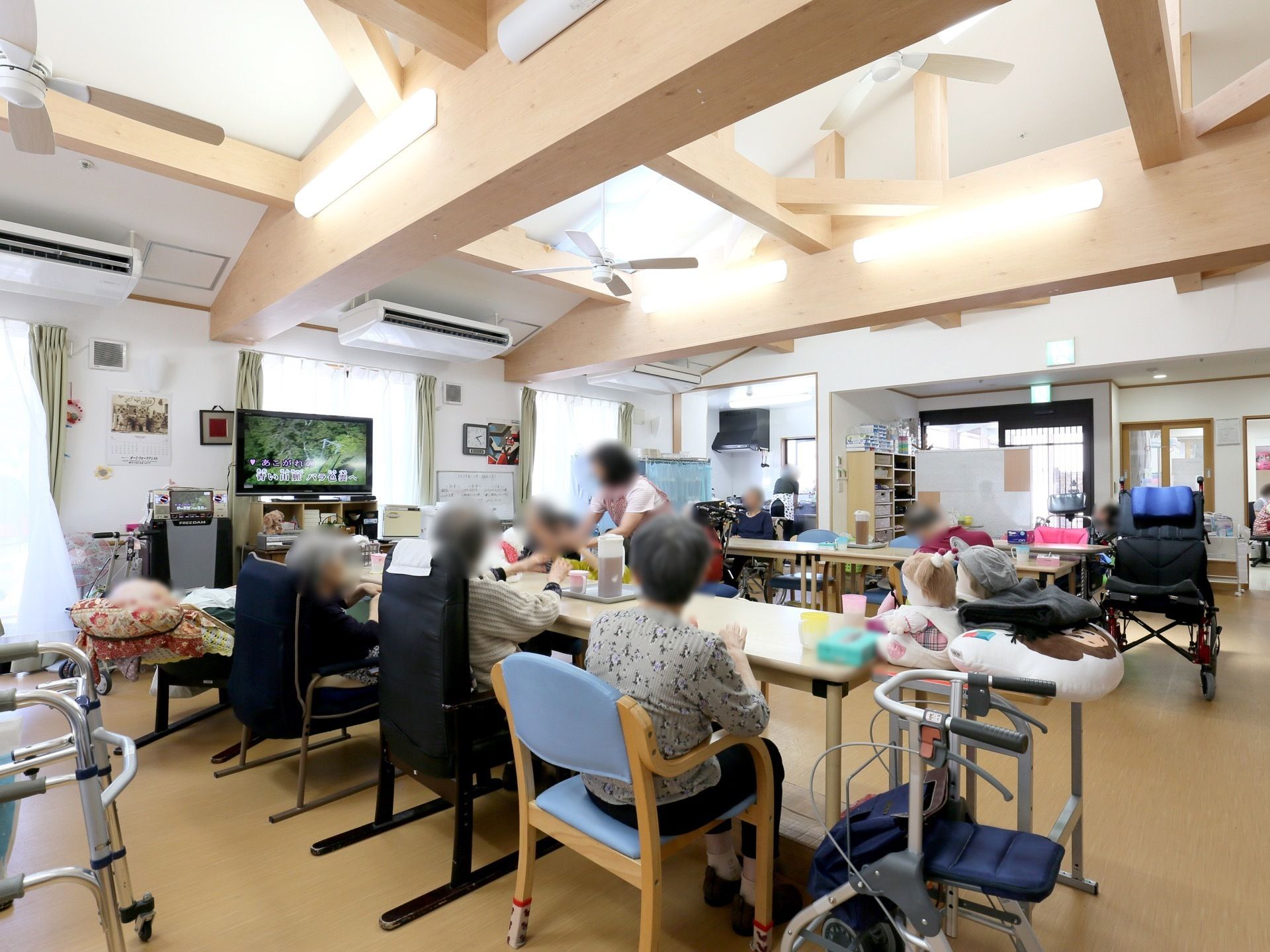 共有スペースは天井が吹き抜けになっており、さまざまな太さの梁が通っている。窓際に大型液晶テレビが置かれている。