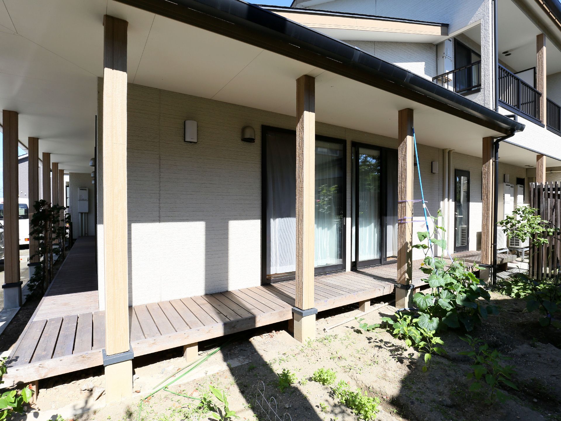 掃き出し窓と野菜畑の間にウッドデッキが設置されている建物