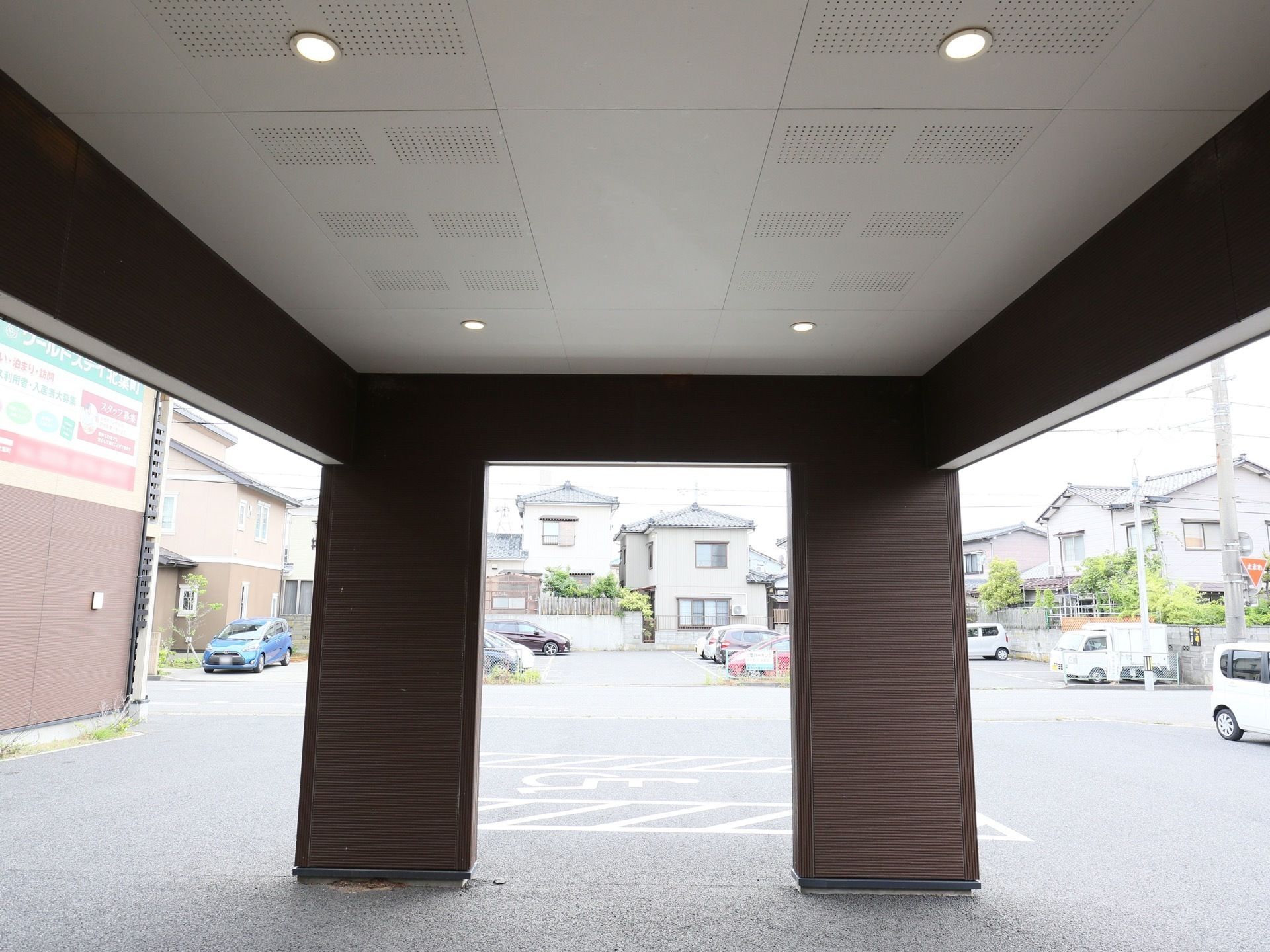 玄関前には大きな屋根がせり出しており、２本の柱で支えられている。天井には４か所に照明が埋め込まれている。