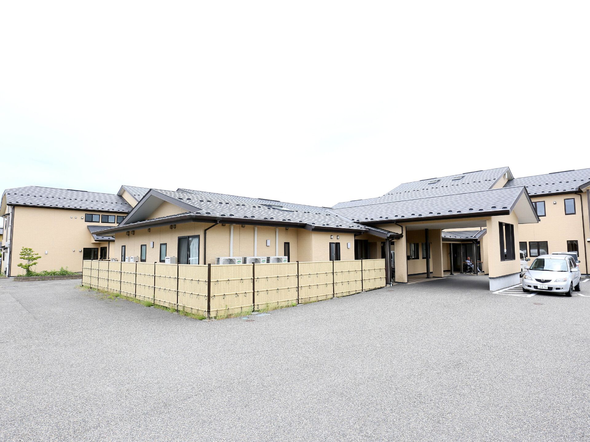 大きな三角屋根の車寄せや、車いす専用の駐車スペースがある建物