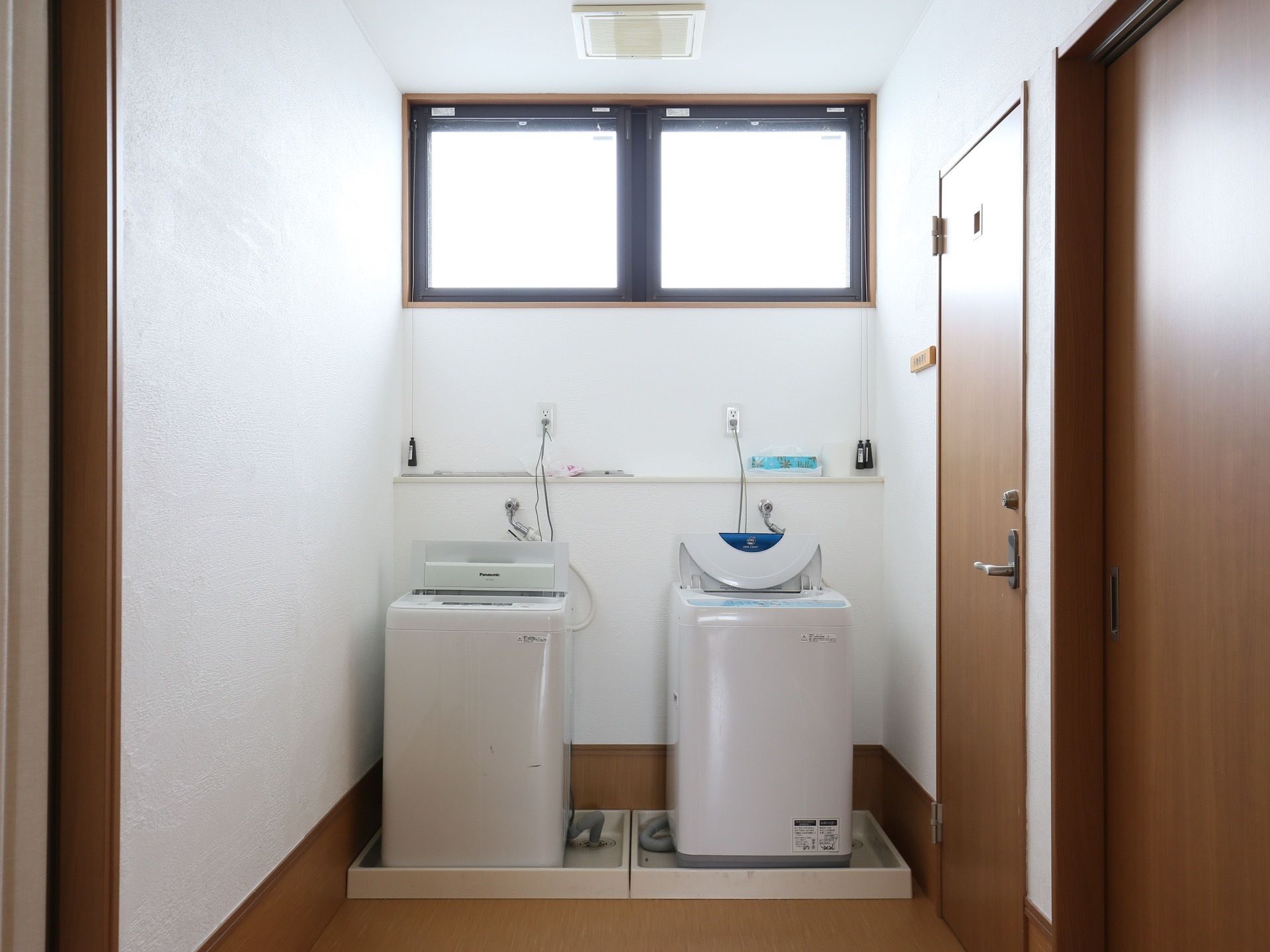 ランドリールームには、2台の洗濯機が並べられている。右側には、木目調の扉が2ヶ所取りつけられている。