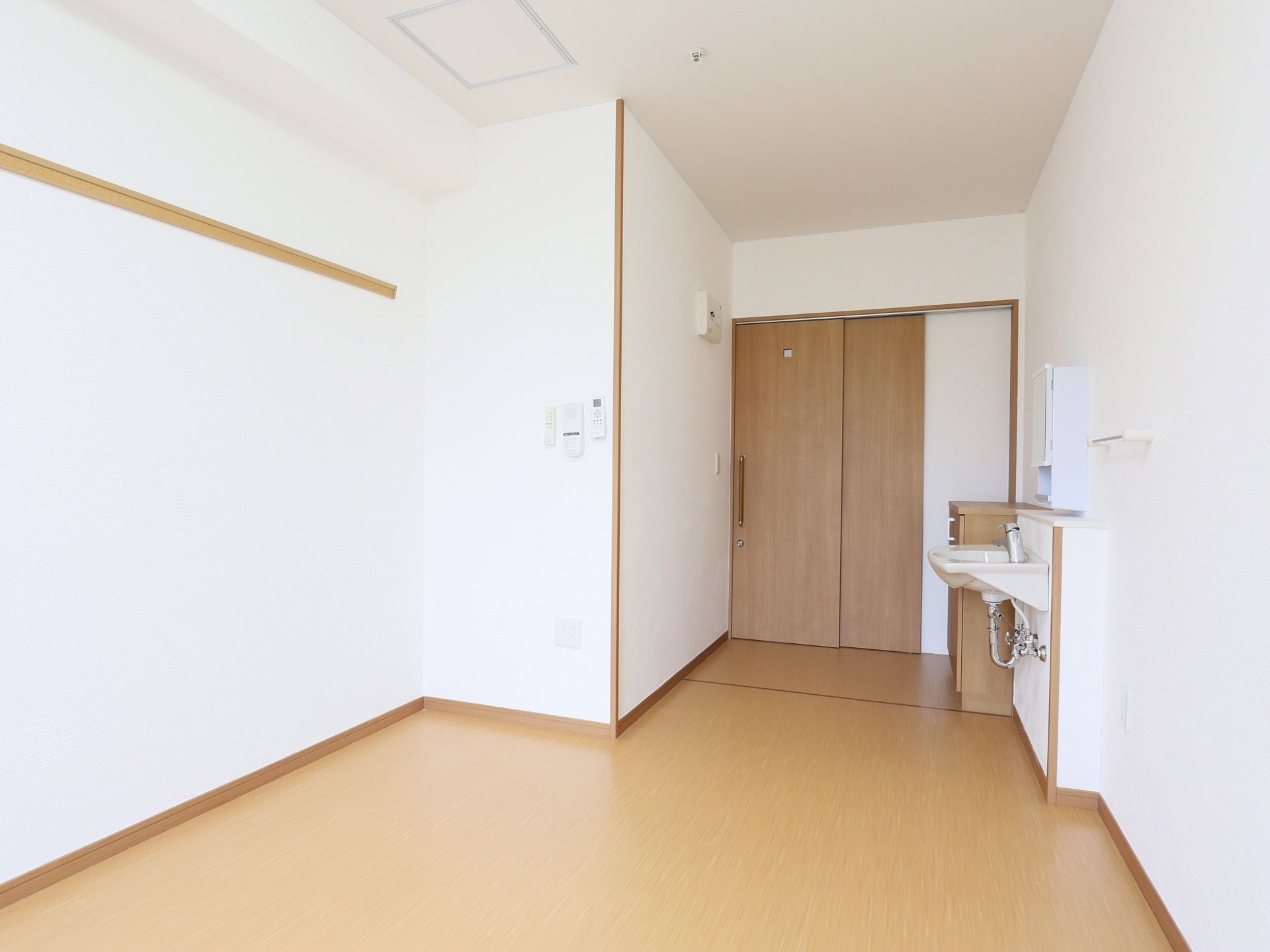 居室は奥行きがあり、白い壁とフローリングのシンプルな内装となっている。入口のそばには、簡易洗面台も完備されている。