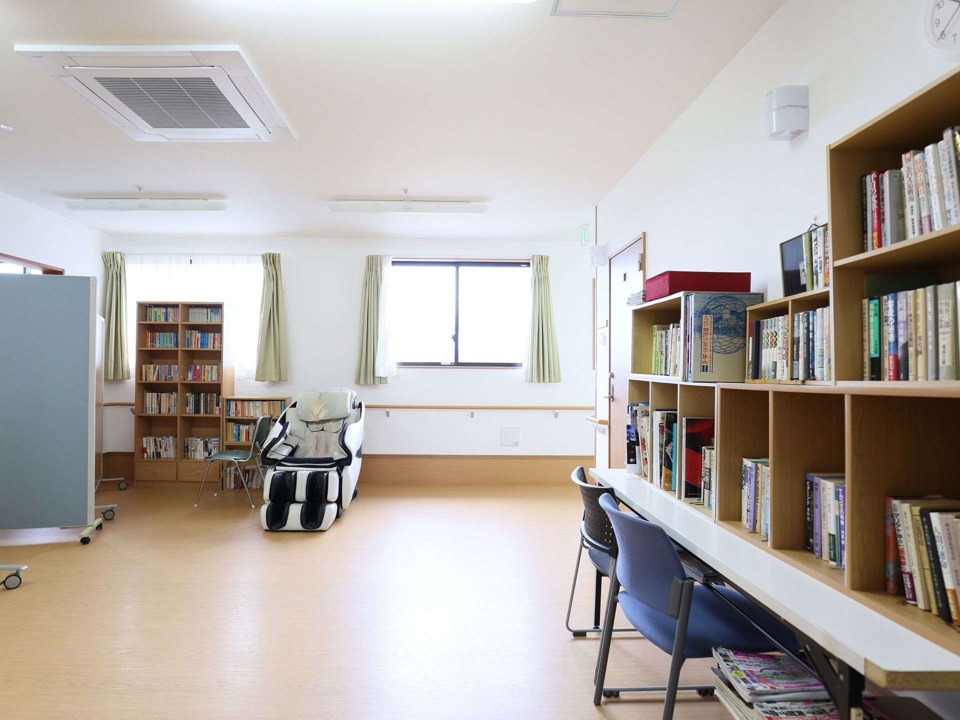 ゆったりとした広さの共有スペースには、たくさんの本が並べられている。天井には、大きなエアコンも設置されている。