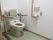 淡い緑の床から落ち着きを感じるトイレである。手すりやクッション、非常用呼び出しブザーが完備されている。