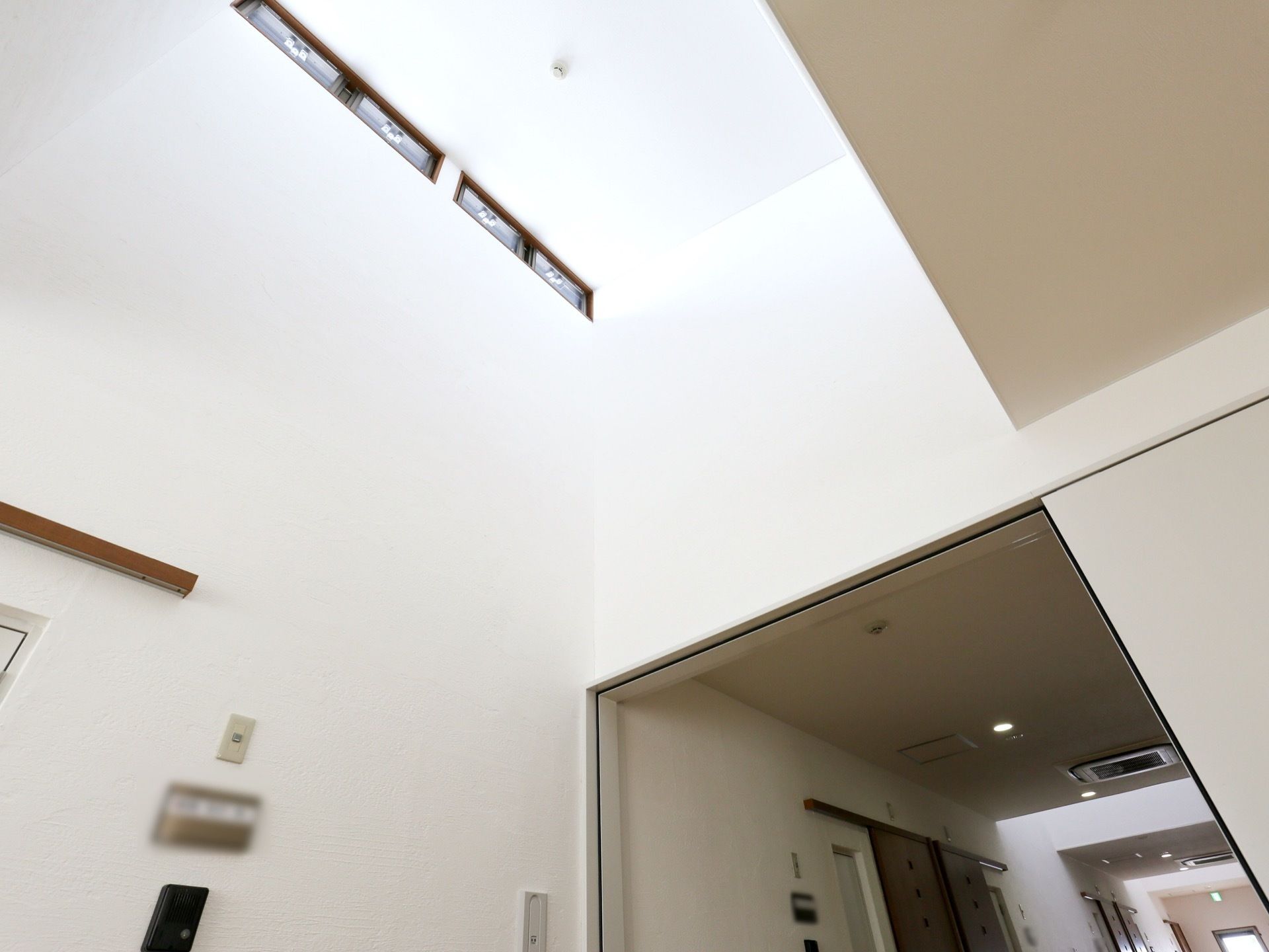 通路上の高い位置に、開閉式の天窓が４面取り付けられている。下の方の壁には、表札プレートと呼び出しチャイムがある。