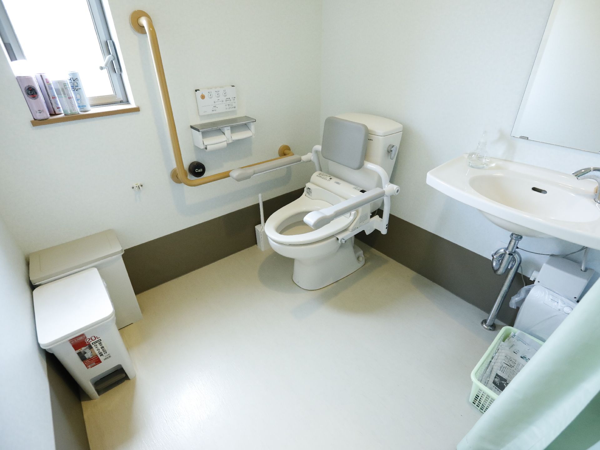 トイレの角にごみ箱が二つ置いてある。小さな窓がある。温水洗浄がついた洋式トイレで操作パネルは壁についている。