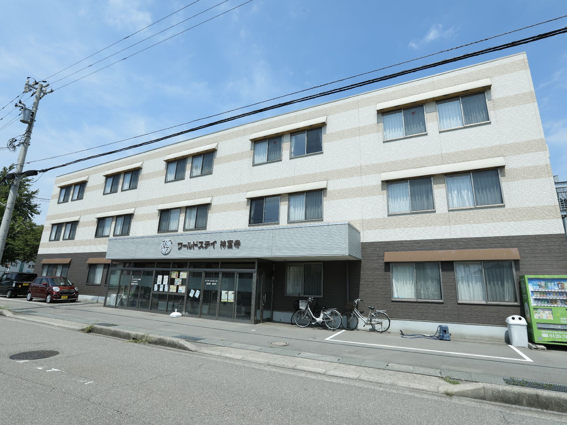 施設の玄関右手には自転車が二台とめてある。車一台分の駐車スペースがある。左手には、車を四台駐車できる。