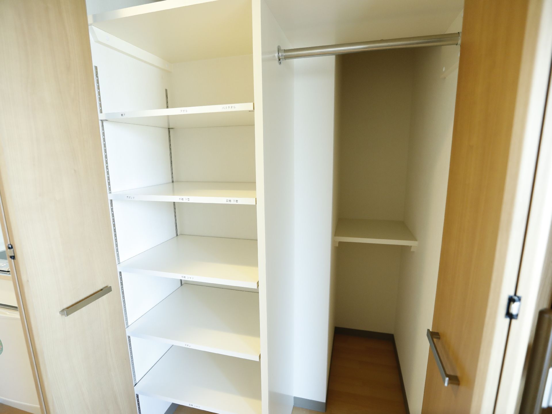 IH調理器具があり、その下にワンドアの冷蔵庫がある。隣に棚が四段ほどある収納がある。二段の棚がある。床がフローリングである。
