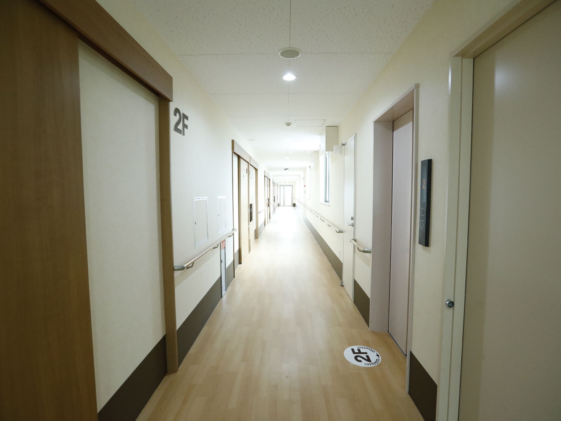 直線の長い通路となっており、右側にエレベーター、左側には「2F」という表示板のつけられた、手すり付きの壁がある。