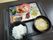 黒いデザインのお盆の上にのった食事は、ご飯とみそ汁の他、何種類かに分けられたプレートにおかずがのっている。