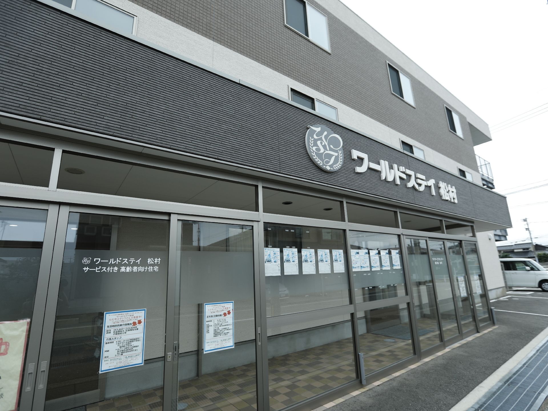 エントランス前に風除室が設置されている、茶色を基調に白のアクセントが印象的な建物