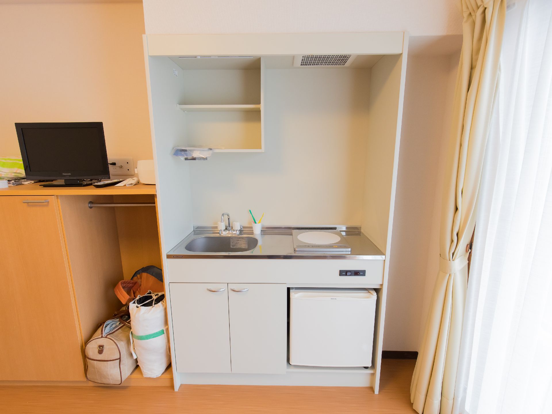 部屋に備わっている、一口のIHクッキングヒーターやミニ冷蔵庫などがあるミニキッチン