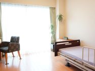 部屋全体に自然光が差し込むフローリングの明るい室内。介護用ベッドのほか、物入やデスクもついていて快適に過ごせる。