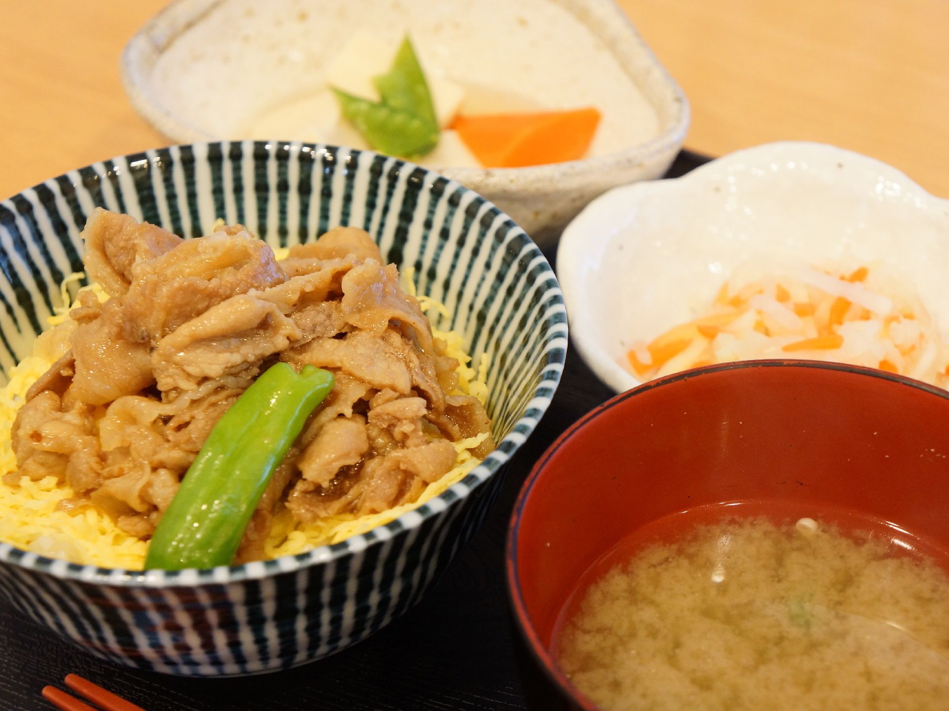 黒いトレーの上に1人分の食事がセットされている。この日のメインは錦糸卵が入った肉丼。味噌汁と副菜2品が添えられている。