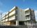 まだ新しい３階建ての建物で、外観は薄いクリーム色のタイル張り。一階の一部が奥に下がっており、そこに玄関がある。