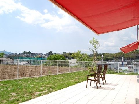 赤い簡易屋根のついたテラスには木製の椅子が設置されている。入居者様は爽快な気分で景色を眺めることができる。