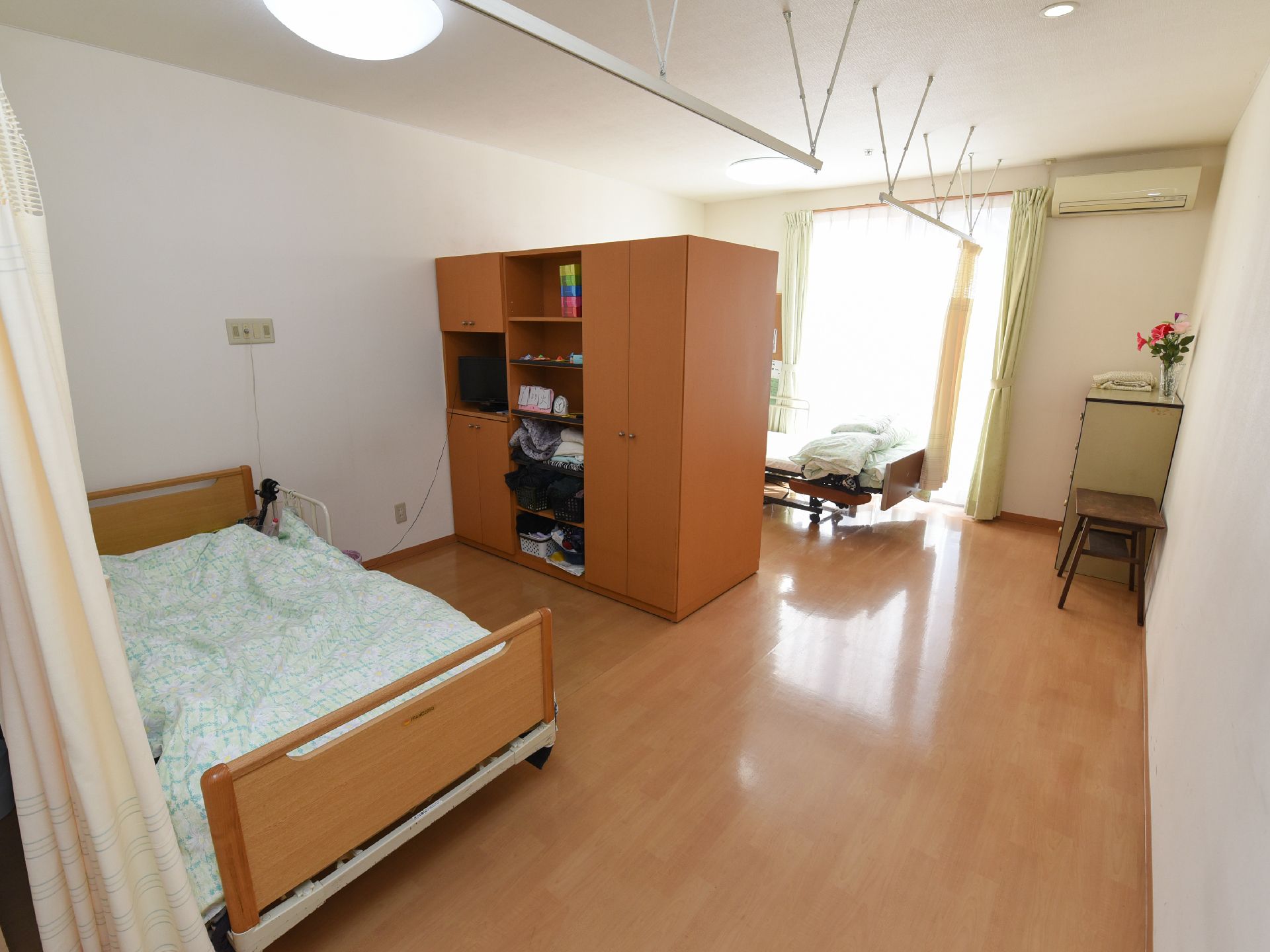 家具で仕切られた相部屋の居室である。通路は幅広く、障害物もない。部屋周りにカーテンレールがあり、個室にできる。