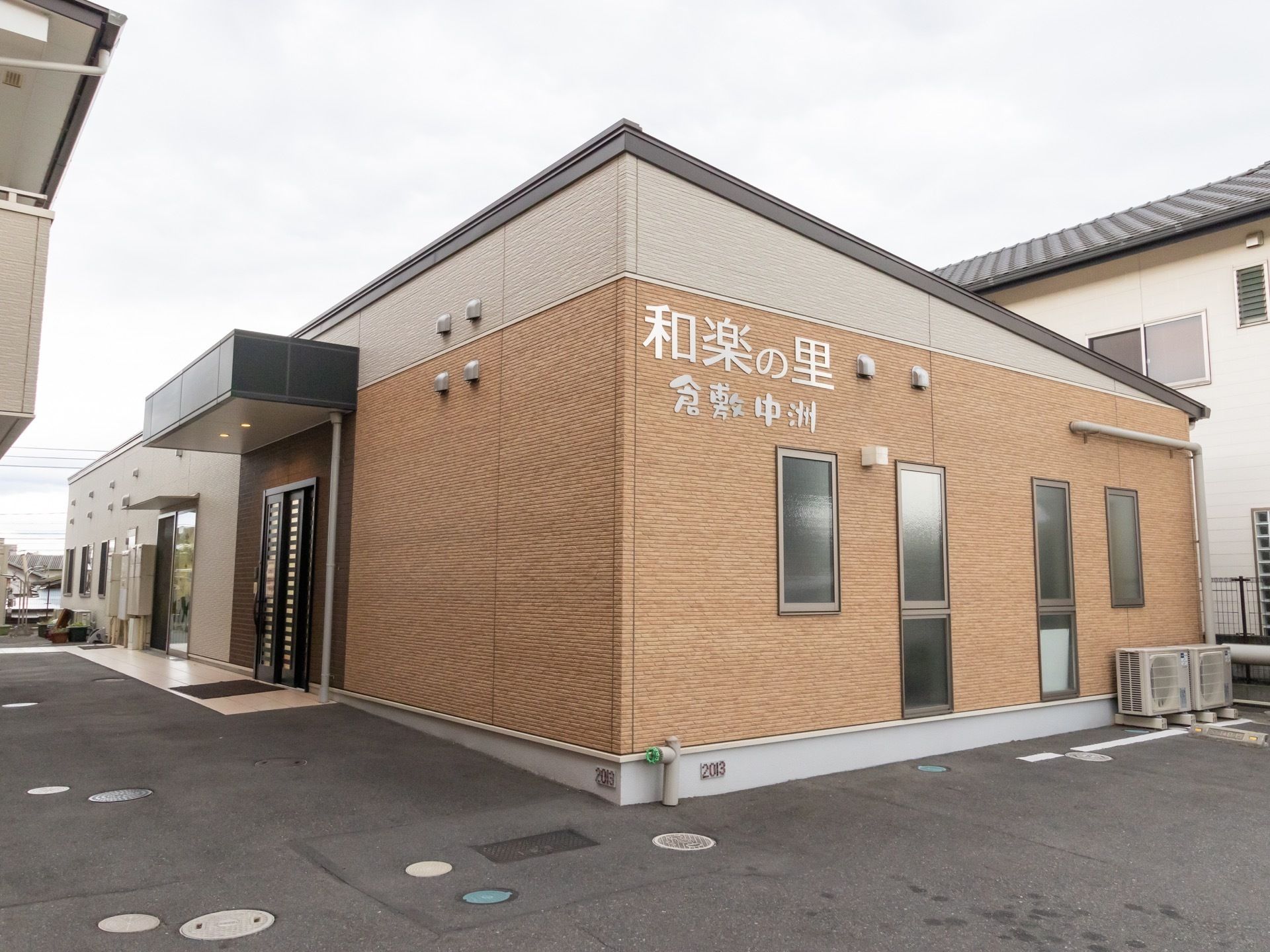 茶系の外壁の平屋建ての建物である。外壁には施設名が取付けられており、その下には、窓が複数並んで設置されている。