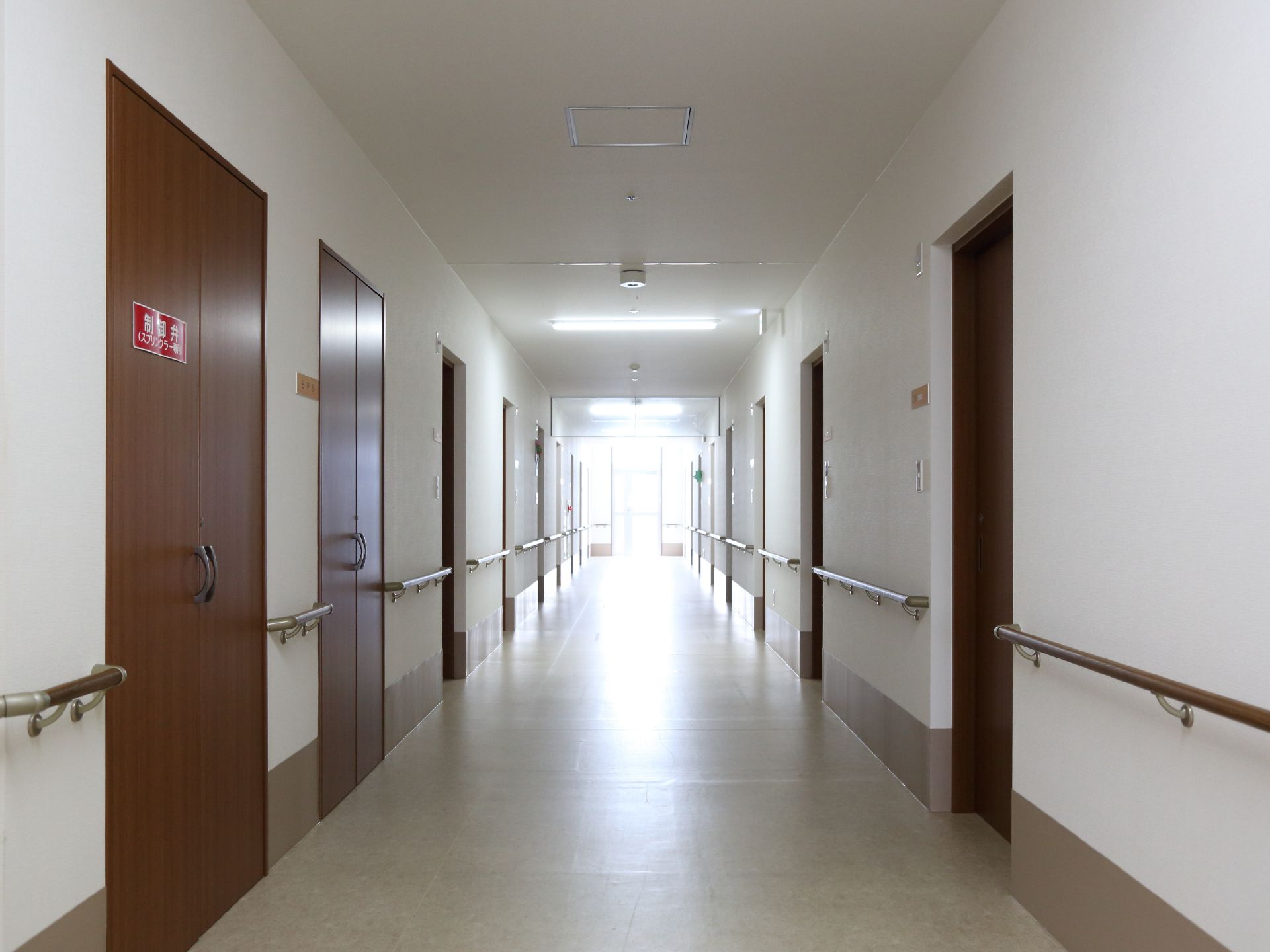 施設内の廊下はまっすぐ伸びていて、居室と居室をつないでいる。廊下の壁には、一面手すりが設置されている。