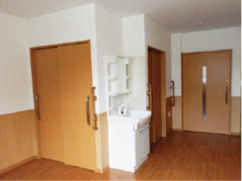 収納や洗面台が付いた白と木目を基調としたフローリングの居室