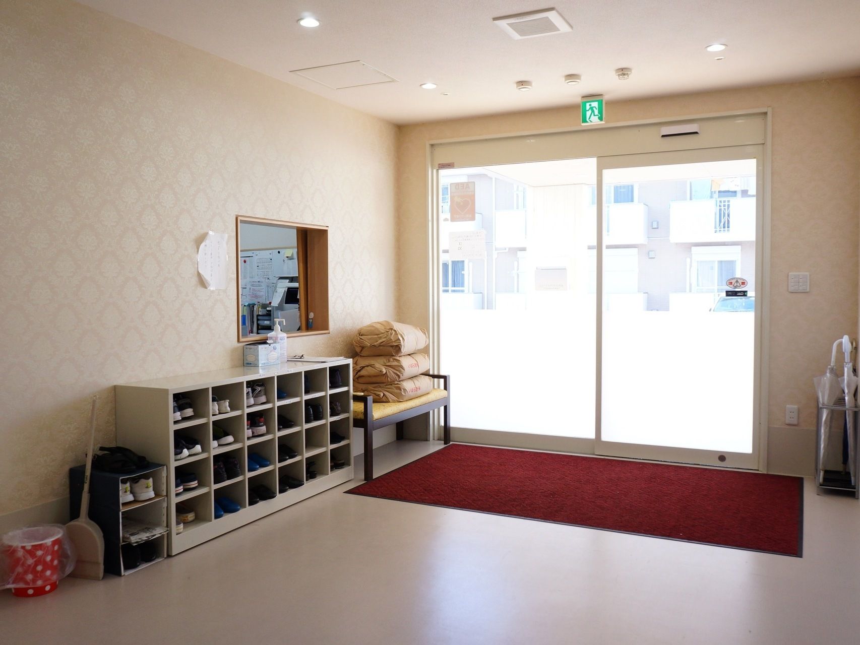 広々とした玄関内である。靴箱の隣にベンチが置かれており、靴の脱ぎ履きの際に便利である。受付の窓がある。