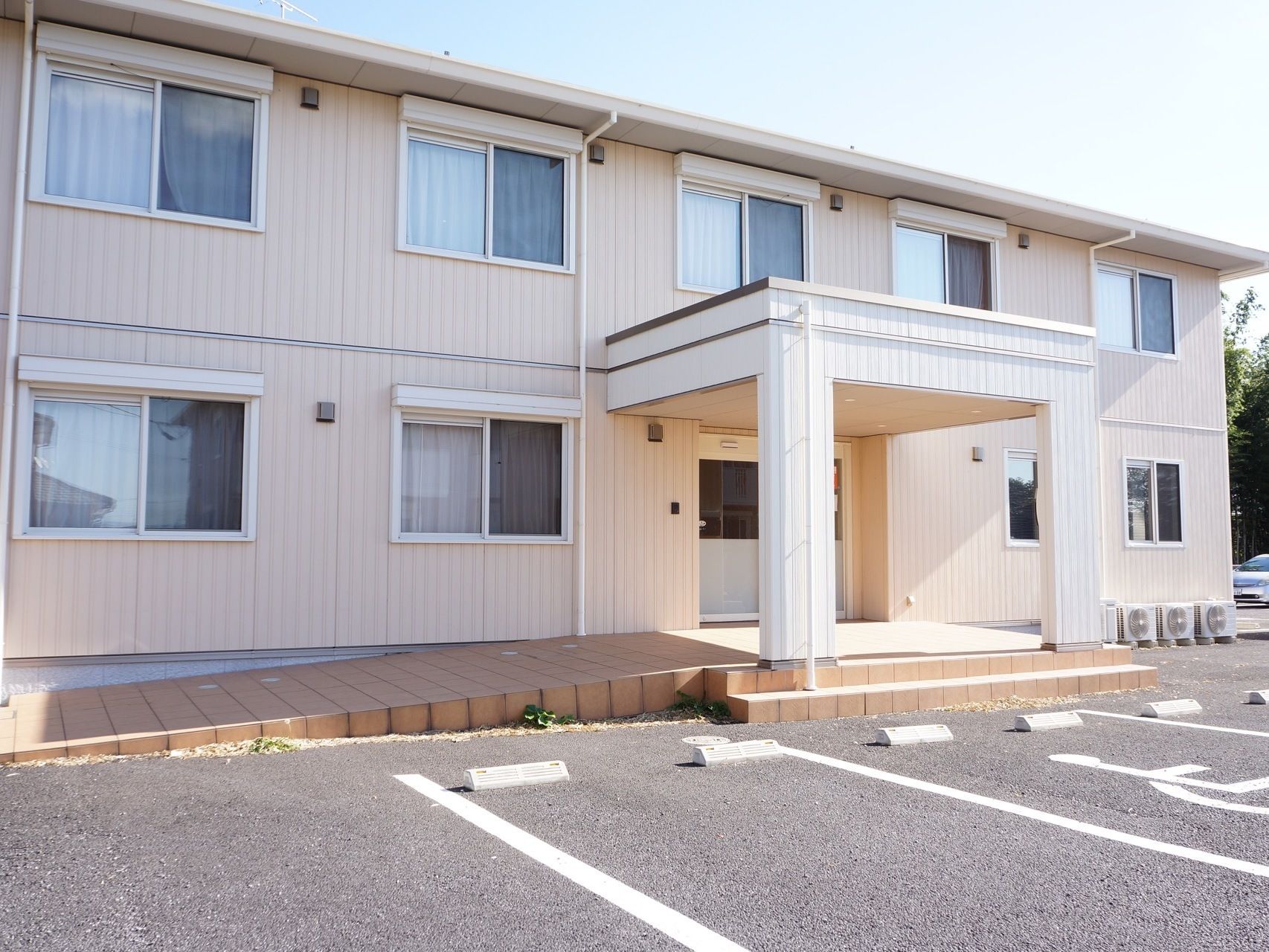 やわらかな色合いの外壁の、二階建ての建物である。入り口には段差の低い階段と、スロープが備わっている。