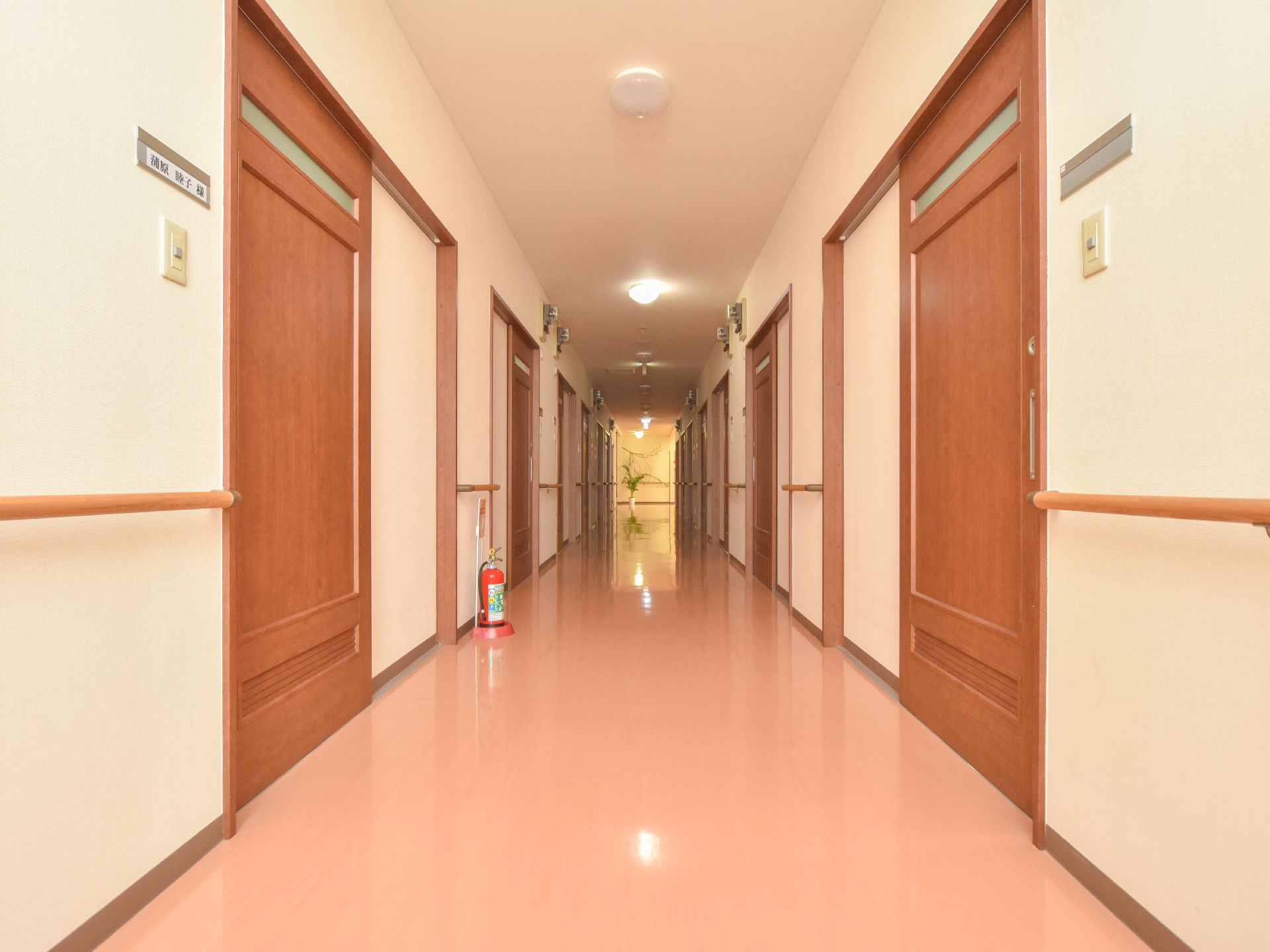 奥行きのある通路の両サイドには、入居者の個人名が書かれた表札が掲げられており、インターフォンも設置されている。