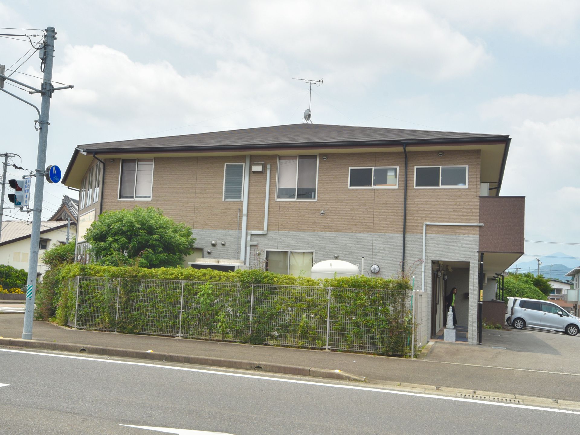 施設の横側部分には豊富な緑が生えているのが良くわかる。また、右手奥には何台かの車を停めることのできる駐車場がある。